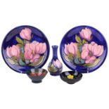 A pair of Walter Moorcroft circular pottery plates decorated with pink magnolia of a dark blue