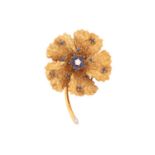A sapphire and diamond flower brooch, realistically designed with textured gold set with a central