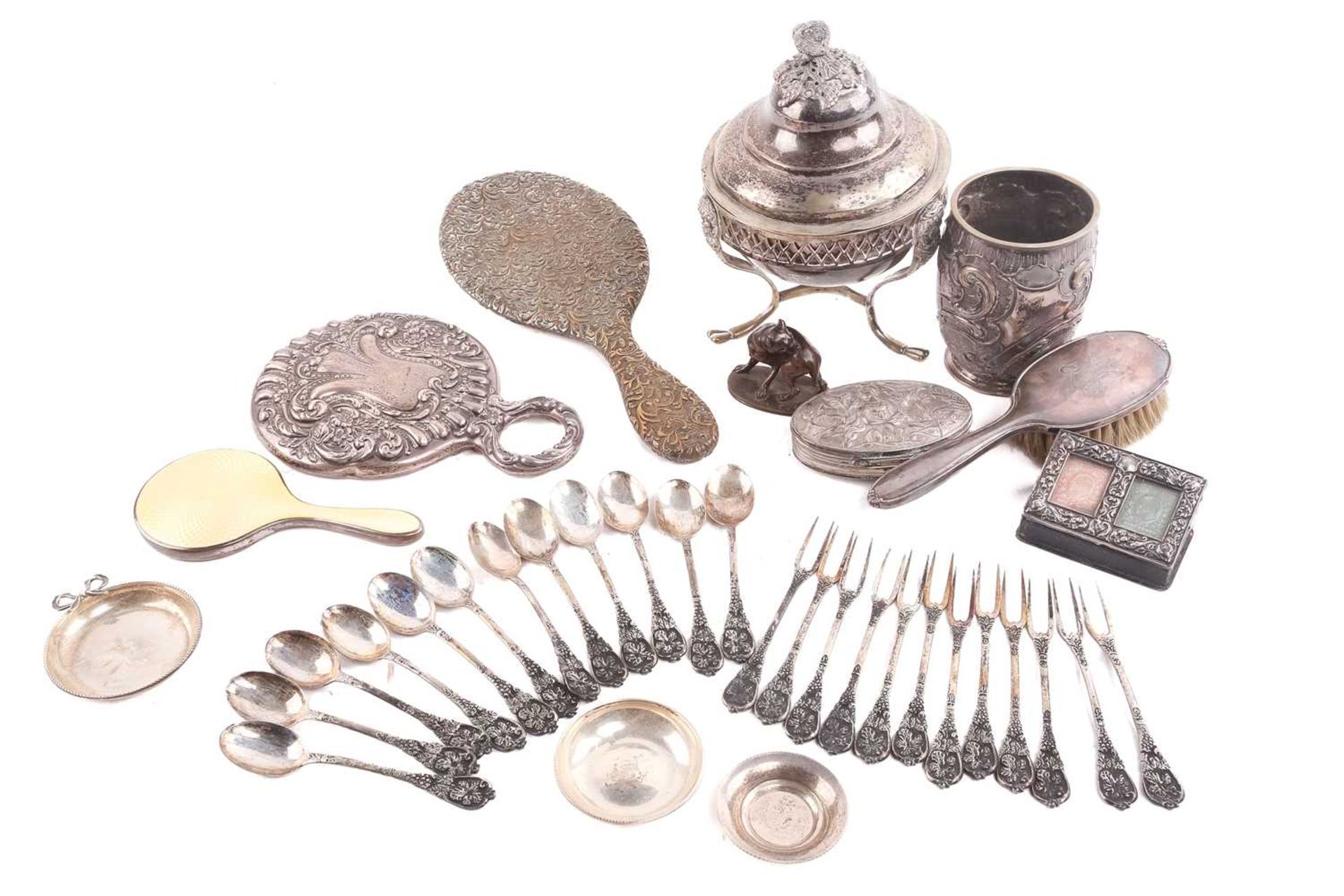 A collection of silver items including a sugar bowl with stand, the cover with a hawk finial,