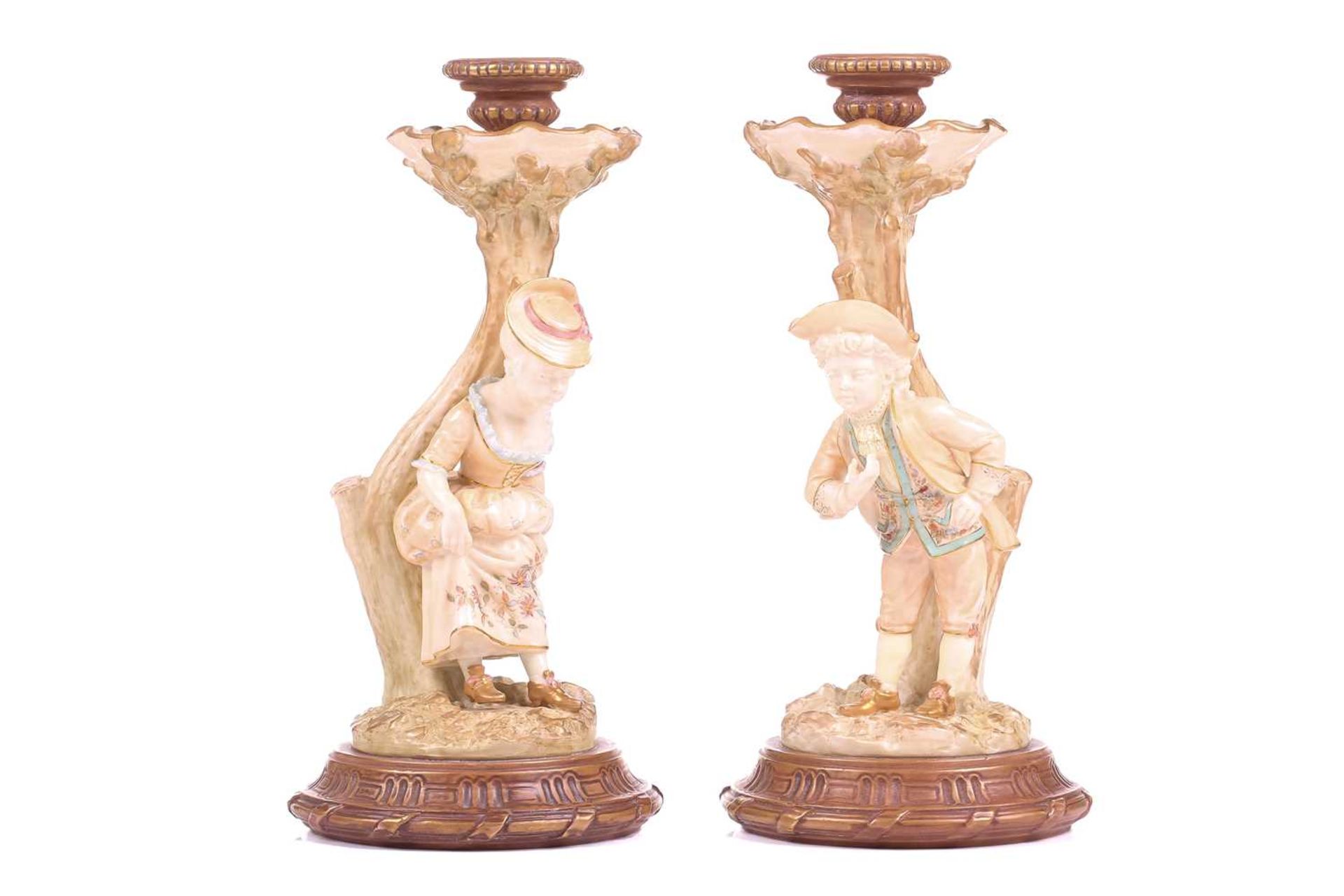 A pair of Royal Worcester figural candlesticks, modelled by James Hadley, as a boy and girl in