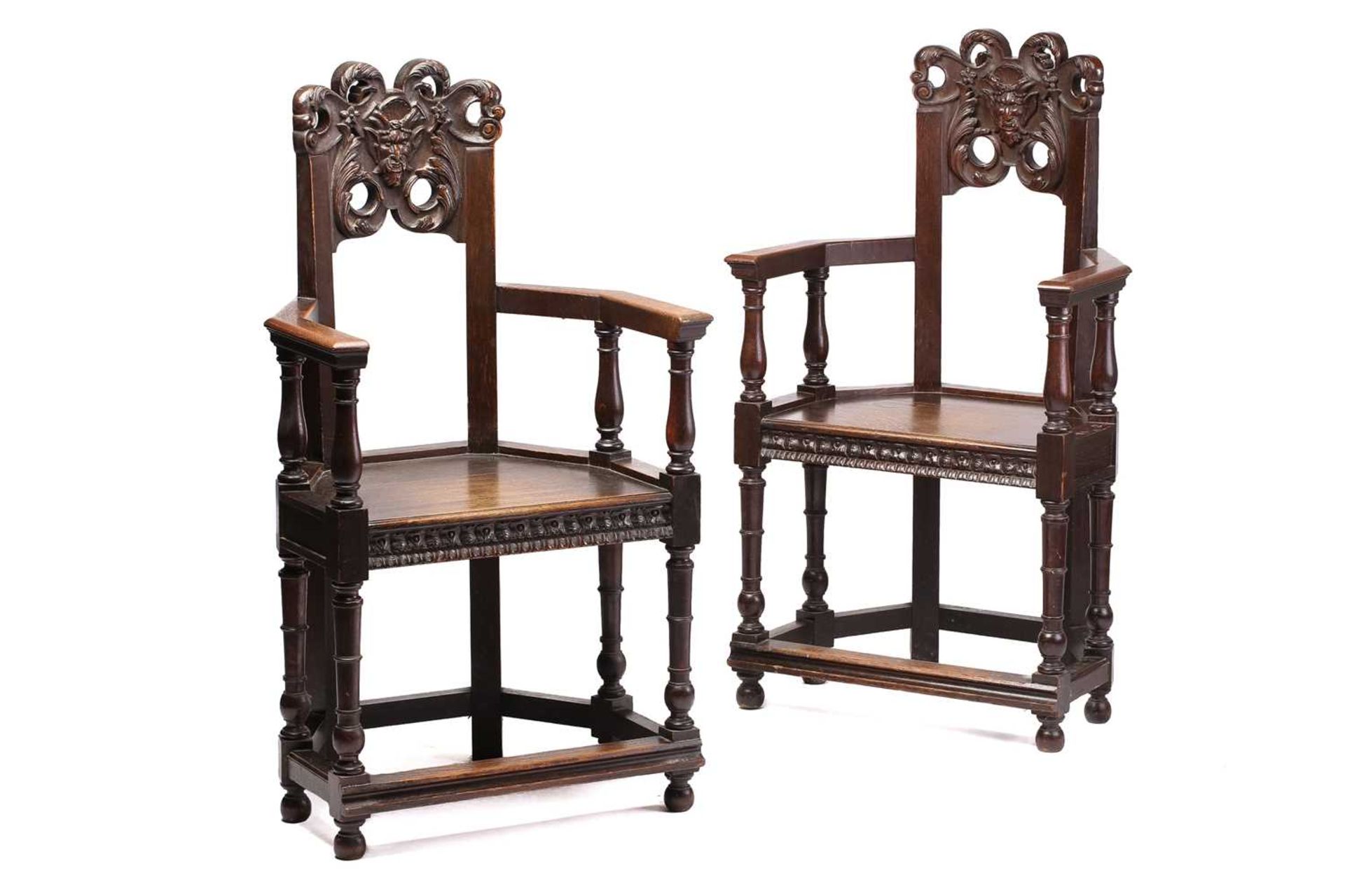 A pair of French carved oak caquetoire armchairs, 19th/20th century, the curved backs carved and