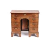 An 18th-century oak kneehole writing desk fitted with a central frieze drawer above a further six