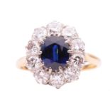 A sapphire and diamond entourage ring, centred with an oval-cut sapphire of deep blue colour,