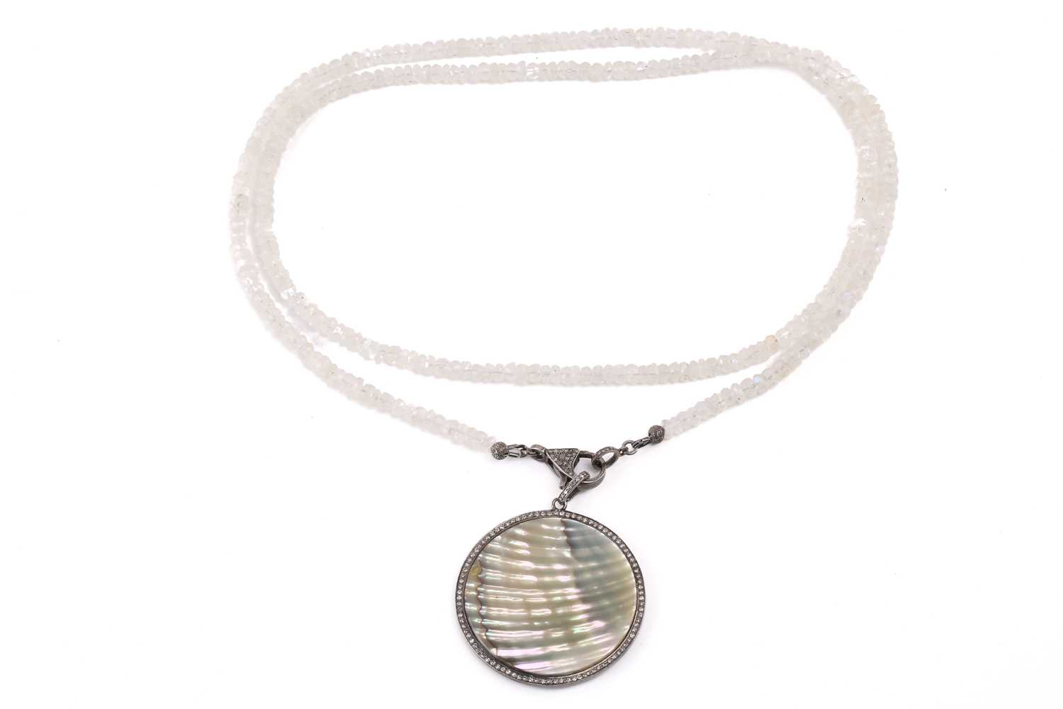A diamond and mother of pearl pendant, the central polished circle of mother of pearl surrounded