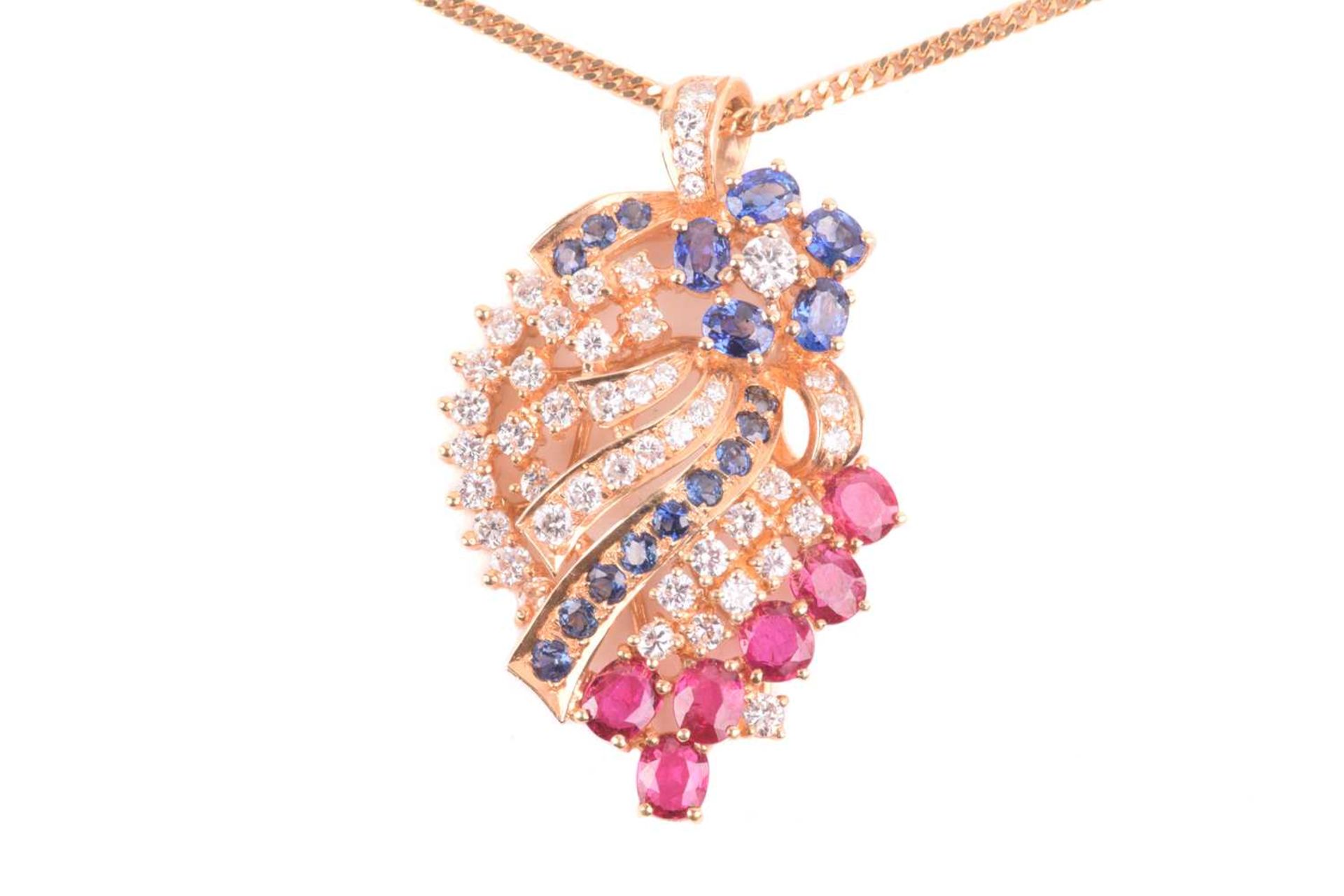 A diamond, ruby and sapphire spray pendant on chain; the stylised spray comprising a six stone