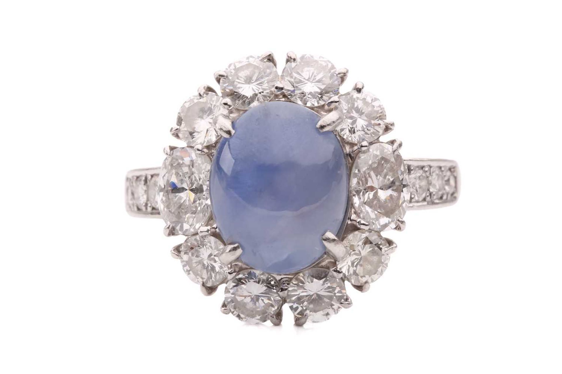A star sapphire and diamond entourage ring, centred with a star sapphire of 9.7 x 7.7 x 6.0 mm, with