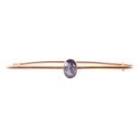 A sapphire-set bar brooch, collet-set with an oval-cut sapphire of pale greyish-blue colour,