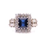 A sapphire and diamond entourage ring, featuring a rectangular step-cut sapphire of deep blue