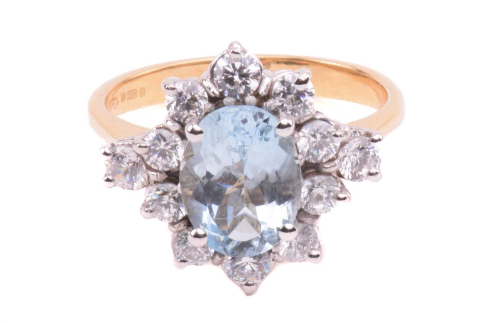 An aquamarine and CZ cluster ring in 18ct gold, comprising an oval-cut aquamarine of light blue
