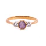 An amethyst and diamond three stone ring, set with a central amethyst measuring 4.8mm x 4mm x 2.6mm,