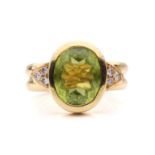A peridot and diamond dress ring, collet-set with an oval-cut peridot of 12.0 x 9.4 x 5.4 mm,