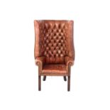 A George III style mahogany and brown hide porters armchair, 20th century, with deep buttoned