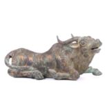 A Chinese bronze and gilt recumbent bull, possibly Zhou dynasty or later, the animal with one leg