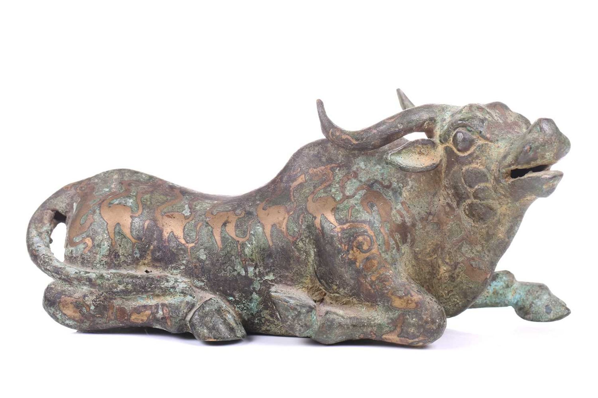 A Chinese bronze and gilt recumbent bull, possibly Zhou dynasty or later, the animal with one leg