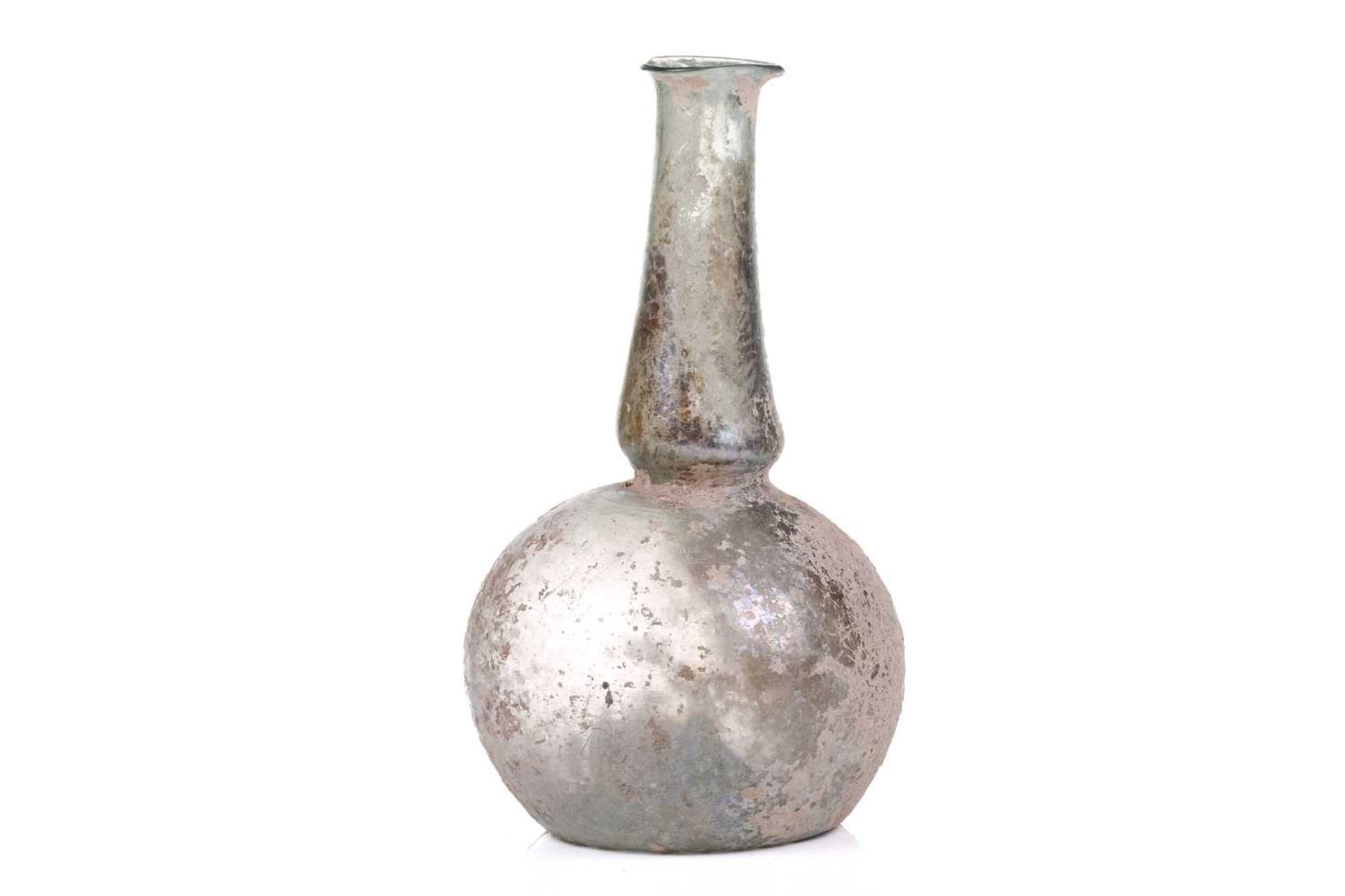 A Roman glass bulbous flask with everted rim, signs of oxidation and encrusted soil to the