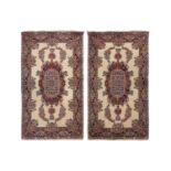 A pair of ivory ground Kerman rugs with central floral medalion and corresponding corners. 128 cm