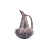 An Etruscan Bucchero-style black pottery jug, with a bulbous ribbed body, tapering slender neck