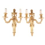 A pair of Louis XVI style gilt bronze twin-branch wall lamps, with flame finials over ribbon