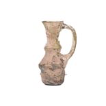 A small glass ewer, probably Syria 10th-12th century, of ribbed form, with a moulded strap handle,