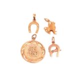 A Chinese pendant with a symbol for prosperity, a Chinese Qilin charm, and two horseshoe charms, all