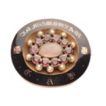 A Victorian garnet, seed pearl and enamel mourning brooch set with rows of garnet and pearls
