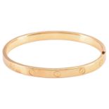 Cartier - a 'LOVE' hinged bangle in 18ct yellow gold, constructed with two arcs engraved with
