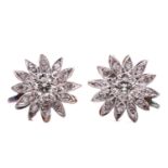 A pair of diamond daisy head earrings, each centred with a yellow tinted brilliant-cut diamond of
