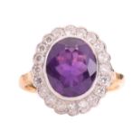 An amethyst and diamond halo ring, featuring an oval-cut amethyst of 11.7 x 9.8 x 5.8 mm, collet-set