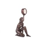 A contemporary patinated bronze figure of a female nude, kneeling and holding aloft a JW Benson