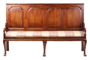 A George III oak four-panel settle, probably West Midlands, with stepped arch panels above a