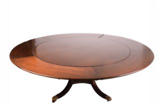 A Regency-style mahogany extending circular dining table with tangential leaf extensions, the base