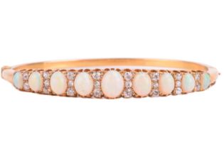 A Victorian opal and diamond hinged bangle, the bracelet features a graduated row of nine oval