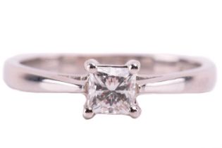 A single stone diamond ring; the princess diamond in four claw mount, to tapered shoulders and plain