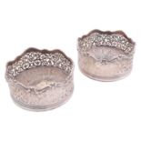 Robert Garrard. A pair of Victorian silver wine coasters, circular with cast scroll borders and