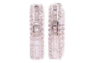 A pair of diamond-set huggy hoop earrings in 9ct white gold, both set with a central row of