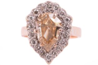 A diamond cluster ring, set with a shield shape fancy colour champagne diamond with an estimated