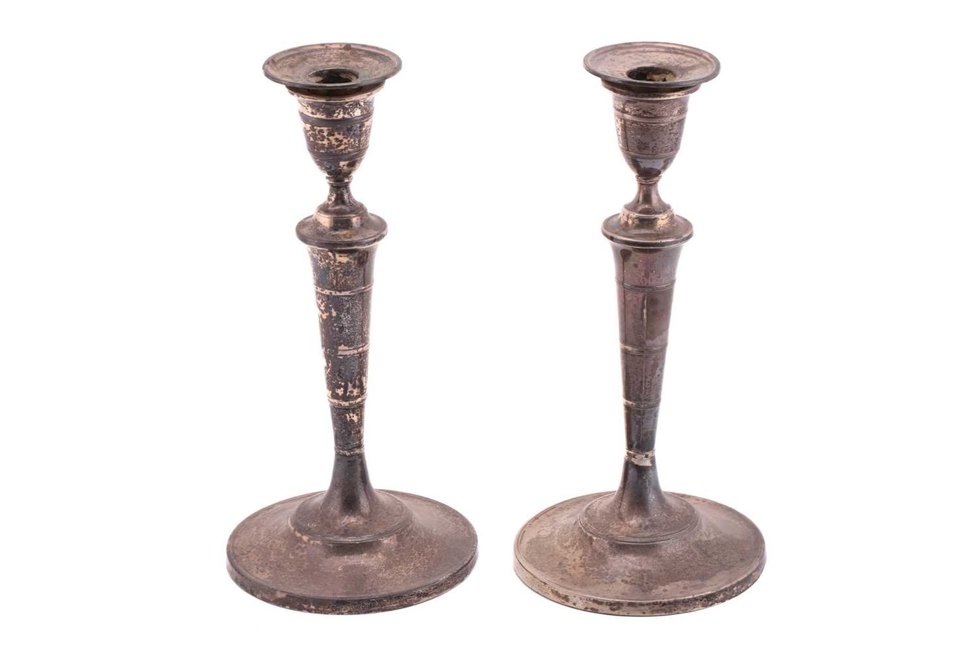 A pair of late George III silver candlesticks, of round form with flared round weighted bases,