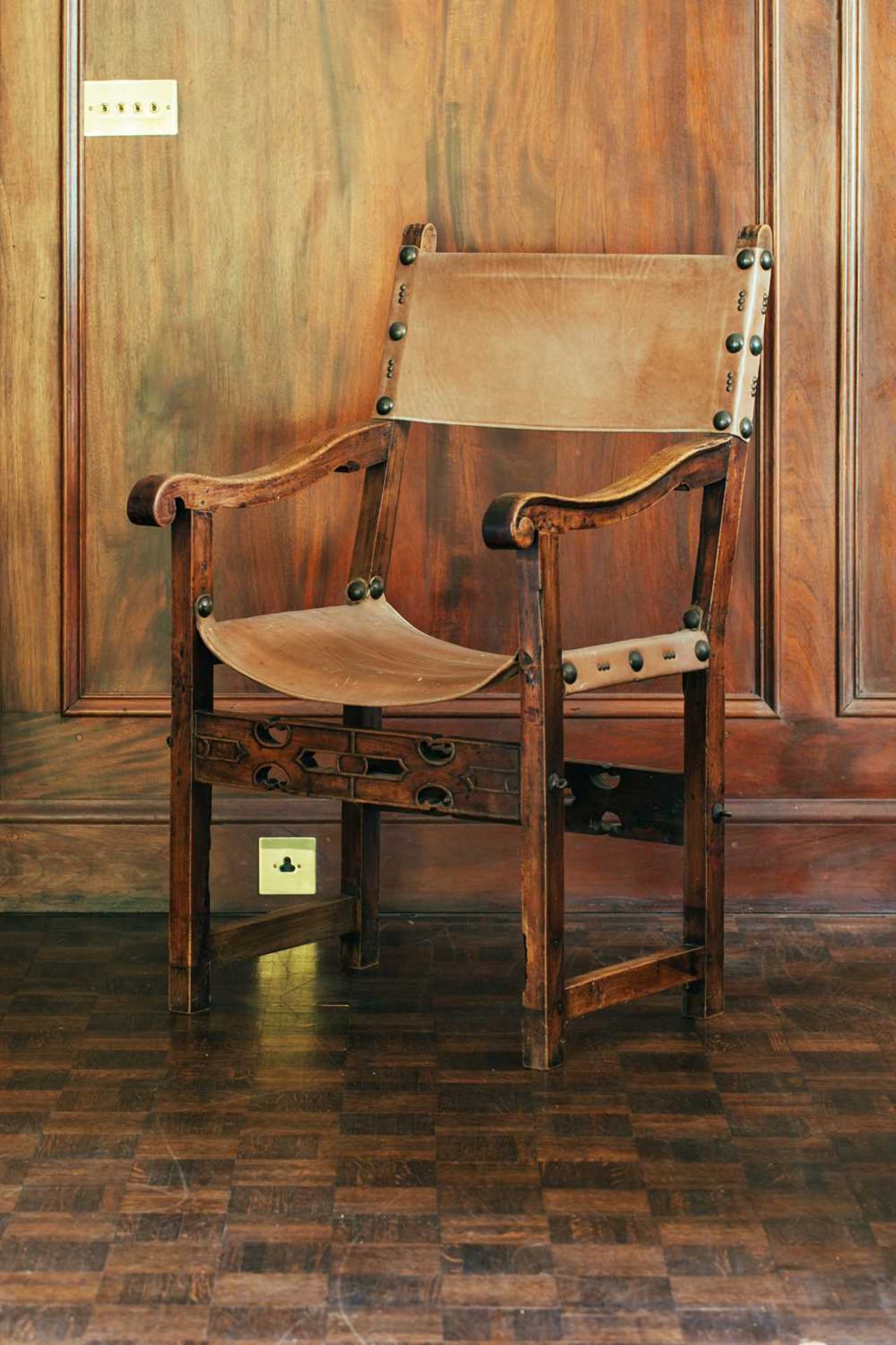 A 17th-century style leather slung open armchair, with pierced and carved front seat rail, 106 cm