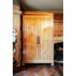 A 19th century Continental maple armoire, the moulded cornice over a pair of panelled doors, on