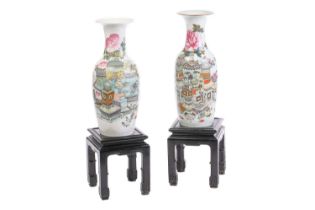 A pair of Chinese famille rose baluster vases, depicting vases of chrysanthemums, books, bowls of