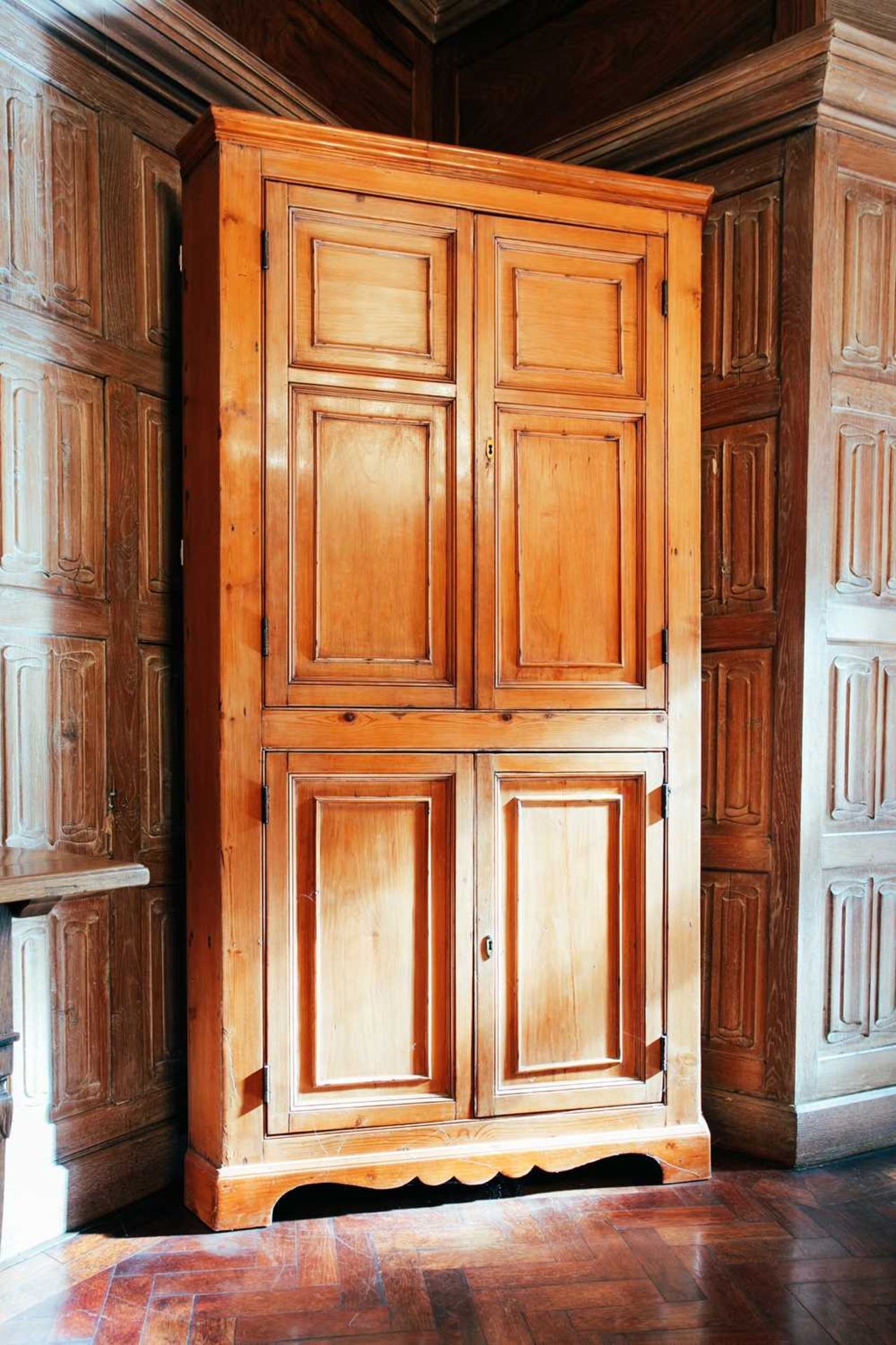 An early 19th century pine corner cupboard, with pair of panelled doors above another similar