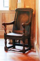 A 17th century oak panel back open armchair, panel seat on turned and stretchered supports.