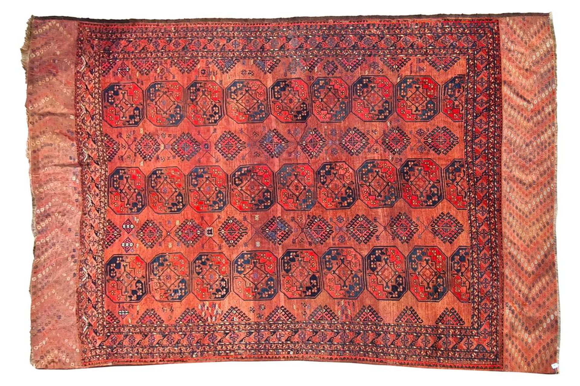 A large antique "Old country house" red ground Afghan carpet, with three rows of elephant foot