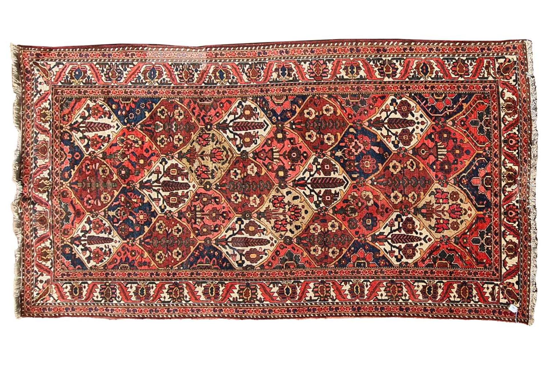 A red ground Baktiari carpet, with an allover compartmented design within multiple borders, 302 cm x