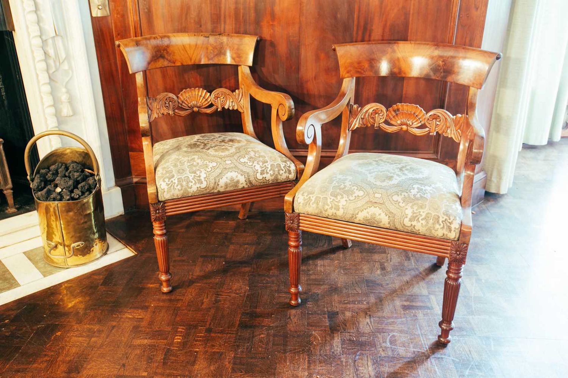 A pair of 19th century Continental mahogany open armchairs, with curved top rails and fan carved mid