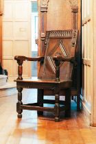 A 17th-century oak wainscot chair, with carved panel back and panel seat, on turned stretched