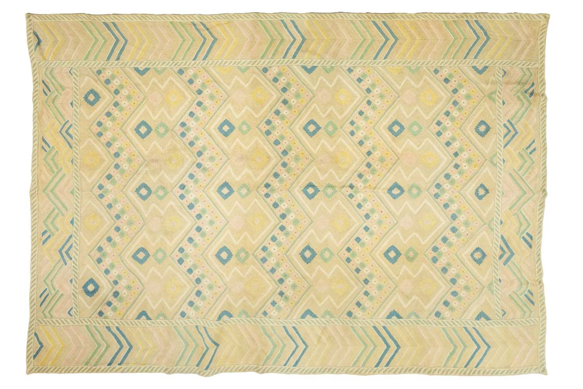 A large 'Mid-Century Vintage' style needlework rug in geometric patterns with muted tones of ochre