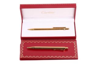 A Les Must de Cartier pen and another; the boxed 'Trinity' ballpoint pen has a gilt ribbed barrel