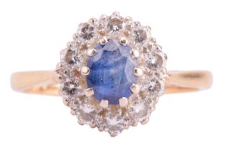 A sapphire and diamond halo ring in 18ct gold, centred with an oval-cut sapphire with bright blue