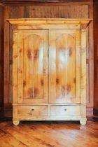 A large Biedermeier maple and fruitwood armoire, the moulded cornice over two panel doors and two